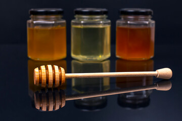 Hexagonal jars with different types and colors of fresh flower honey and a honey spoon. vitamin food for health and life