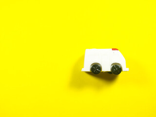 Fototapeta na wymiar White ambulance toy on a yellow background with copy space.