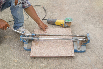 man hand cutting a tileby using a tile cutter on the floor, selective focus