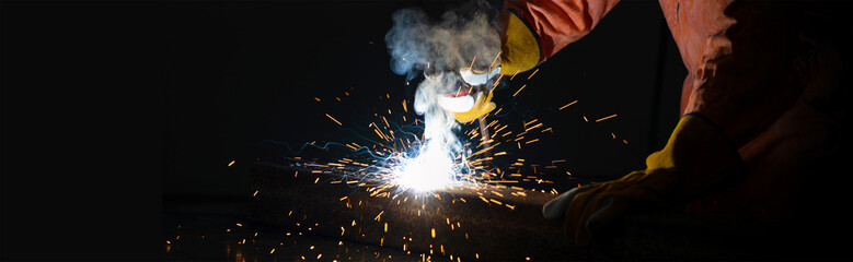 Closeup metal industry worker's hand welding steel sheet. Sparkler on black background. Heavy work...