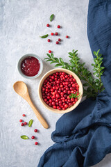 juicy forest lingonberry with handmade jam  in a wooden bowl on white table with blue napkin....