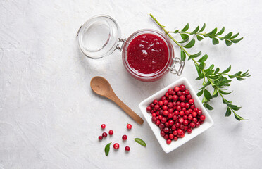 Concept flat lay with homemade lingonberry jam and forest cowberry in bowl on white background. ...