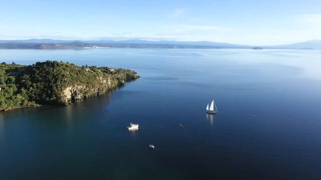 Boats on lake Taupo with bright sunlight, Mine Bay Maori Rock Carvings