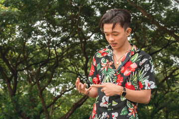A young Filipino man in a hawaiian shirt counts with his fingers. Trying to list mentally his tasks...
