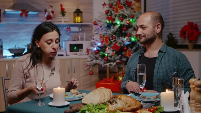 Shocked woman getting asked to marry partner proposing with engagement ring on christmas eve. Couple engaged and enjoying festive dinner. People celebrating holiday and proposal