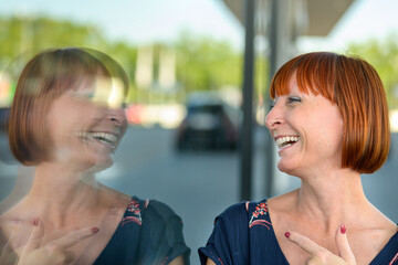 Joyful playful woman laughing and pointing to her reflection