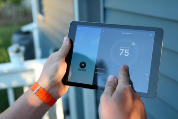 Man is Adjusting a  temperature using a tablet with smart home app