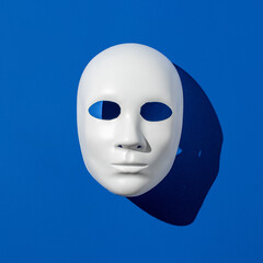 Halloween face mask levitates above the blue background. Minimal holiday season concept. Flat lay.