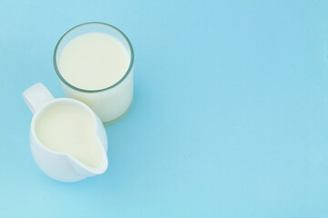 Milk in jug and glass on blue background with copy space 