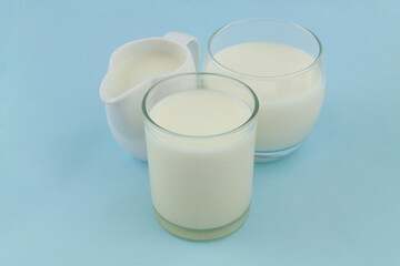 Jug with milk and two glasses of milk on blue background.	