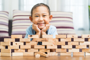 Happy Asian girl play wooden toys at home