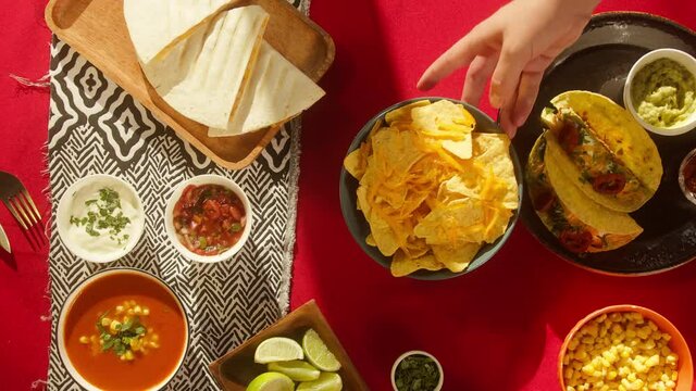 Mexican food on table. Traditional tex mex cuisine. Corn nachos, meat tacos served with vegetables and salsa, tomato soup with cilantro, guacamole. Setting the table with American dishes top view.