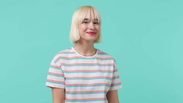 Smiling charming happy amazing vivid young blonde short haircut woman 20s years old wears striped t-shirt looking camera wink eye blink isolated on pastel plain light blue background studio portrait