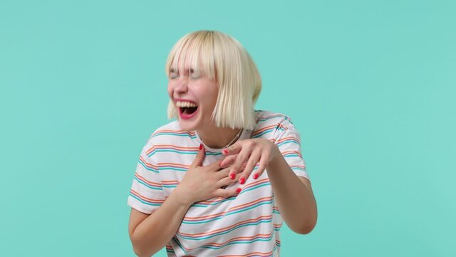 Excited young blonde short haircut woman 20s wears striped t-shirt look camera laugh smiling watch comedy movie point index finger on you isolated on pastel plain light blue background studio portrait