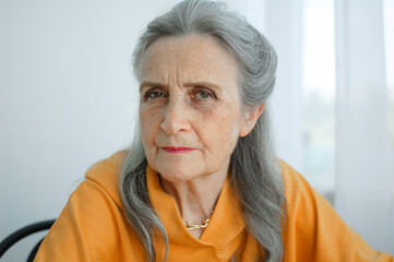 Portrait of beautiful old grandmother with grey hair and face with wrinkles looking at the camera, mothers day, happy retirement