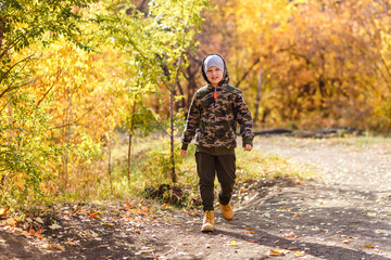 a nine-year-old boy walks in beautiful autumn park. leaf fall in October