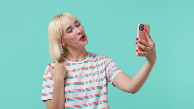 Young blonde short haircut woman 20s wears striped t-shirt get video call using mobile cell phone do selfie talk conduct pleasant conversation isolated on pastel light blue background studio portrait