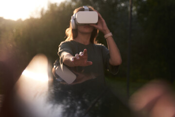 A girl holding virtual reality glasses on her head with her hands. He stretches out one hand to the...