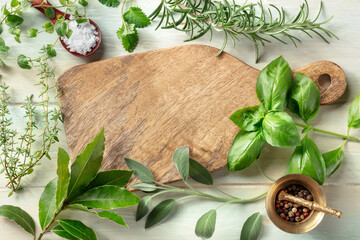 Cooking with herbs. A wooden cutting board with salt, pepper and aromatic herbs. Basil, bay leaf,...