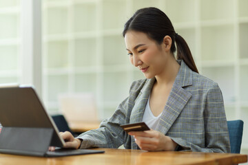 Asian young female entrepreneur using digital tablet to transfer money. holding credit card