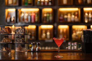 Nightlife concept a glass of pink champaign with a red cherry on the top placing on a wooden bar looking quite appealing
