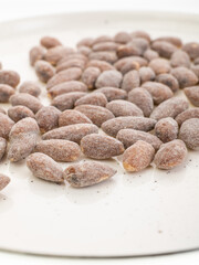 almonds with sweet sprinkles on a plate on a white background