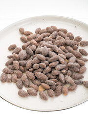 almonds with sweet sprinkles on a plate on a white background