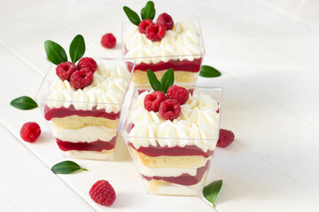 Dessert with raspberry , delicious  dessert with fresh berries., portion dessert in a clear plastic cups. White wooden board, healthy eating , healthy dessert, red berries cake