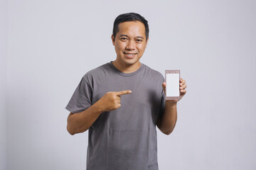 Smiling Asian man pointing his smart phone with blank screen for mock up