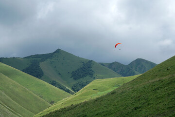 red parachute paraglider in the mountains. Hills. valley