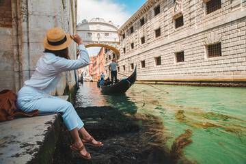 woman sitting at city quay at venice italy enjoying the view of canals with gondolas