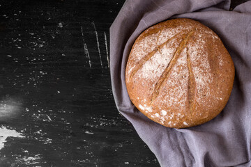 Round loaf of buckwheat bread on dark background