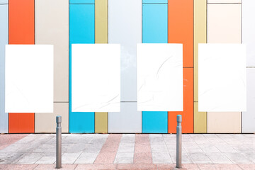 Modern urban scene with colorful geometrical wall and four white glued wrinkled poster templates....