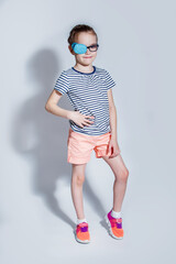 Child girl with an occluder on the eye in a striped jumper on a light background.