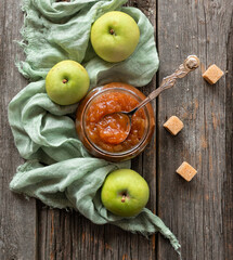 Apple jam in a glass jar with fresh apples and cane sugar on an old wooden table. Top view. Flat lay