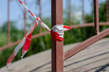 Close-up of the barrier tape tied to the bridge. Red and white tape prohibits passage. Metal...