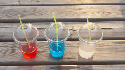 Transparent plastic glasses with soda in three colors red blue white