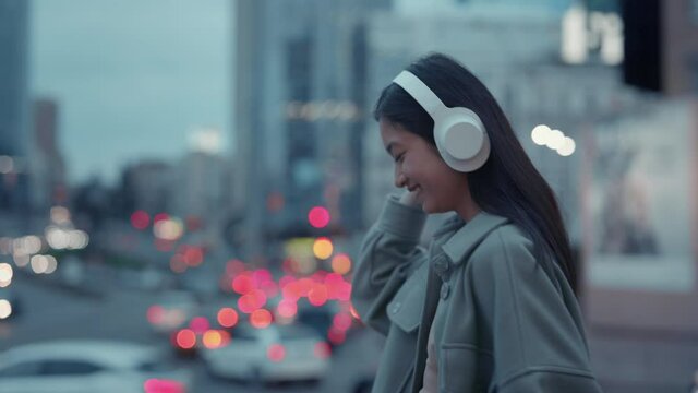 Joyful woman listening music in headphones outdoors