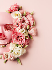 Pastel pink skull face mask with a flower arrangement against matching pink background. Creative Halloween party or Santa Muerte concept. Spooky floral bloom arrangement. Flat lay.