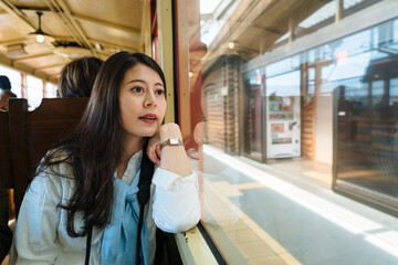 portrait of beautiful asian female visitor is looking at the station through the window while...