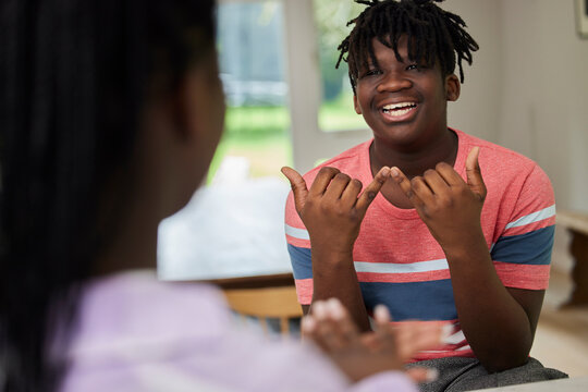 Teenage Boy And Girl Having Conversation Using Sign Language At Home