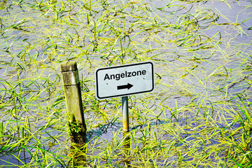 Sign on a body of water. Fishing zone, note in German.