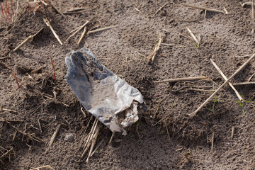 A fragment of an old plastic bottle lying in a plowed field.