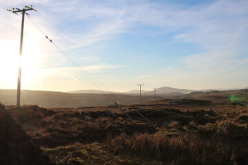 A power line with some mountains in the background during golden hour