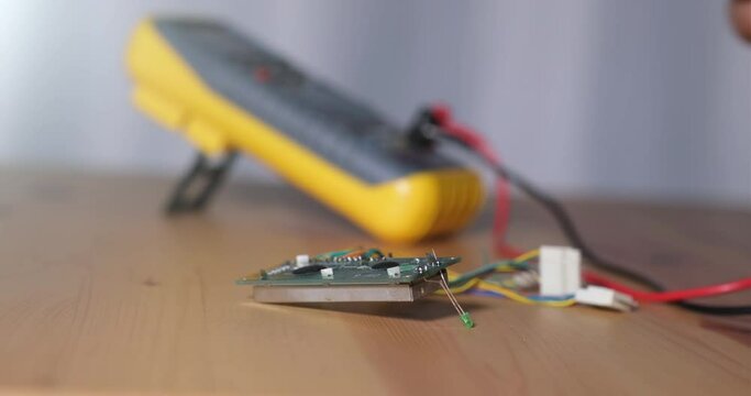 Technician testing the circuit board with a multimeter and measuring the signal in the electrical circuit