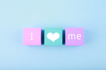 Fototapeta na wymiar Minimal trendy concept of mental health and self love and acceptance. I love me written on multicolored toy blocks in a row against bright blue background