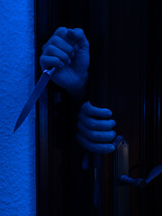 Man with a knife opening a bedroom door. Halloween and violence concept
