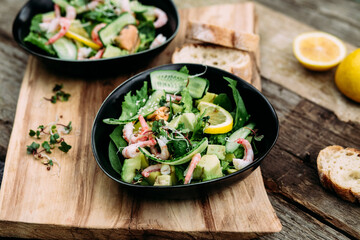 Salad with seafood, vegetables and herbs in a plate on a wooden table. Rustic style