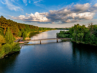 Fototapeta na wymiar Olsztyn Lake Dlugie, bird's eye view. Wooded shores, the sky reflecting in the water table and a bridge over the lake - Warmia and Masuria, Poland