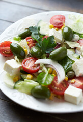 Salad with Feta Cheese, Green Olives, Baby Spinach, Cucumber, Cherry Tomatoes and Capers. Dark wooden background. Close up. 